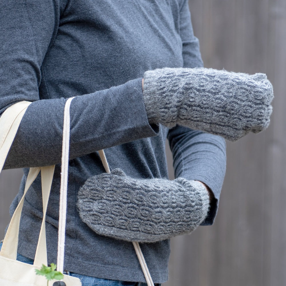 Women’s Recycled Fine Gauge Cable Knit Mittens in Dark Charcoal Heather Grey on figure. Model wearing gloves and holding a reusable tote bag
