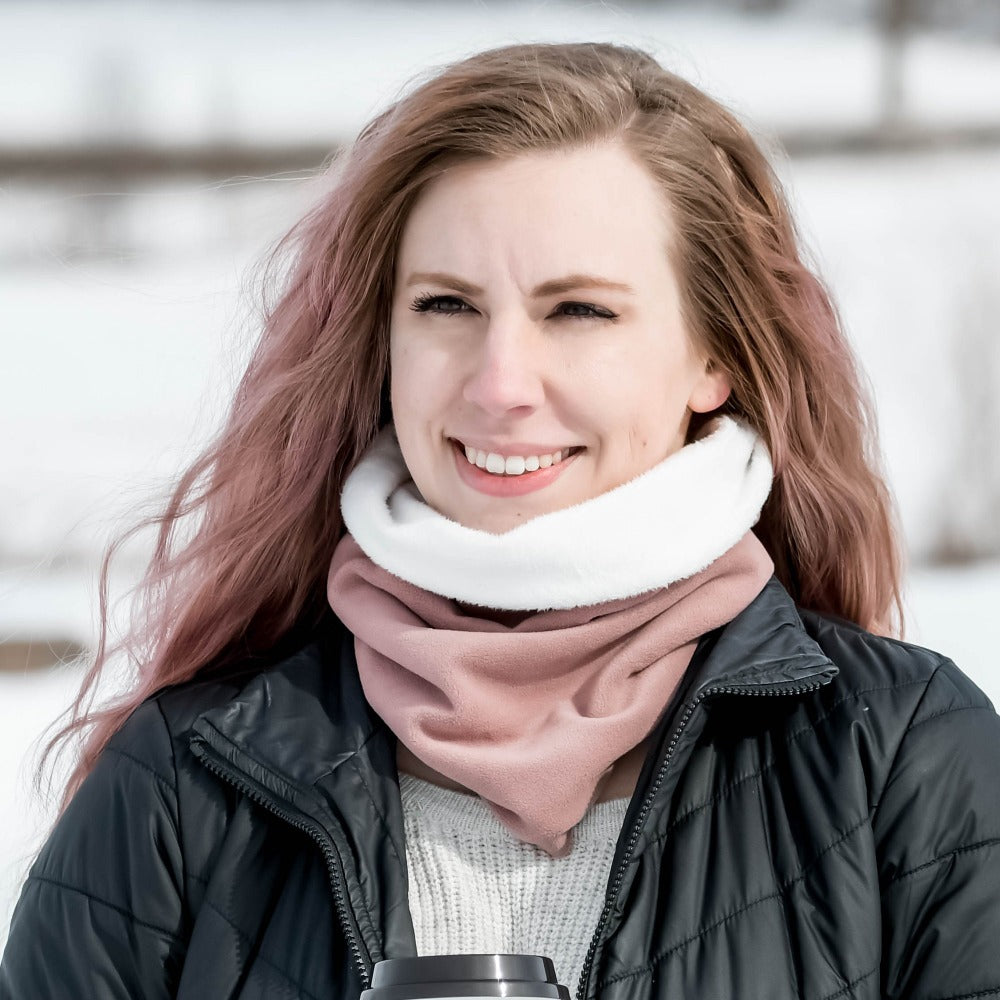 Women’s Recycled Water Repellent Reversible Fleece Scarf in Winter Blossom Pink on figure. Modeling standing with snow around and smiling