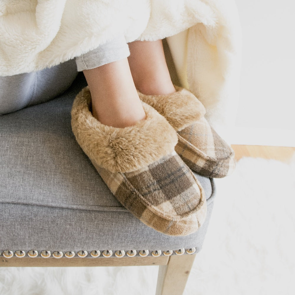 Women’s Print Valerie Bootie Slipper in Taupe on model sitting on the edge of a chair with her feet up, her knees wrapped in a cozy blanket