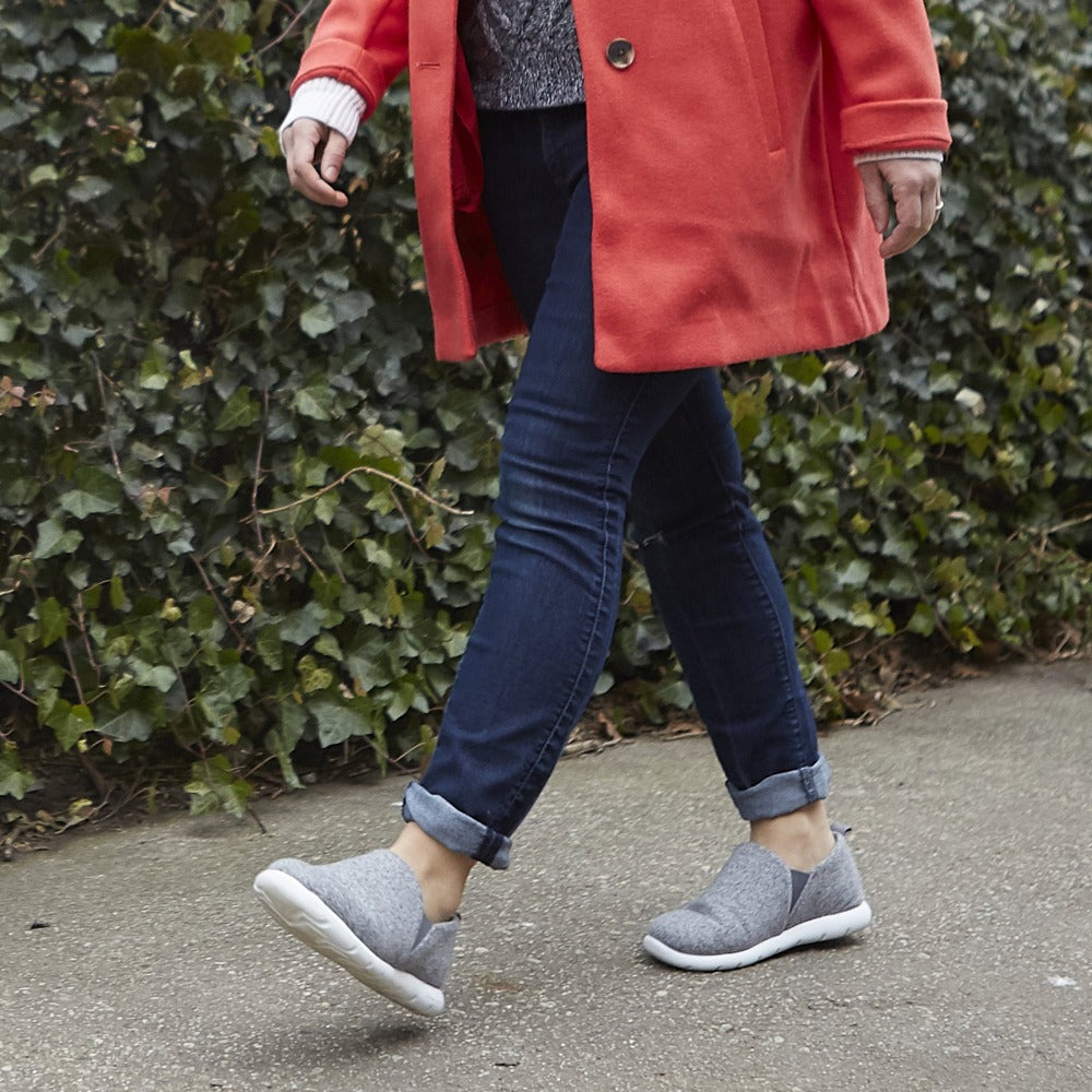 Woman walking on asphalt wearing Zenz Tranquility slipper in heather grey