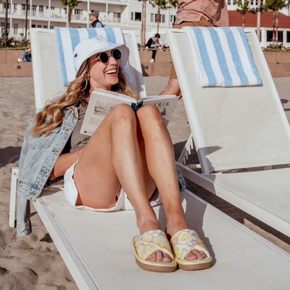 A woman at the beach wearing Floral Keilly slides in lemonade